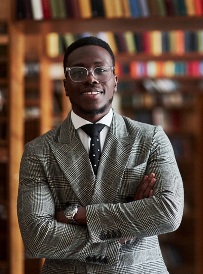 student in front of book shelves in library