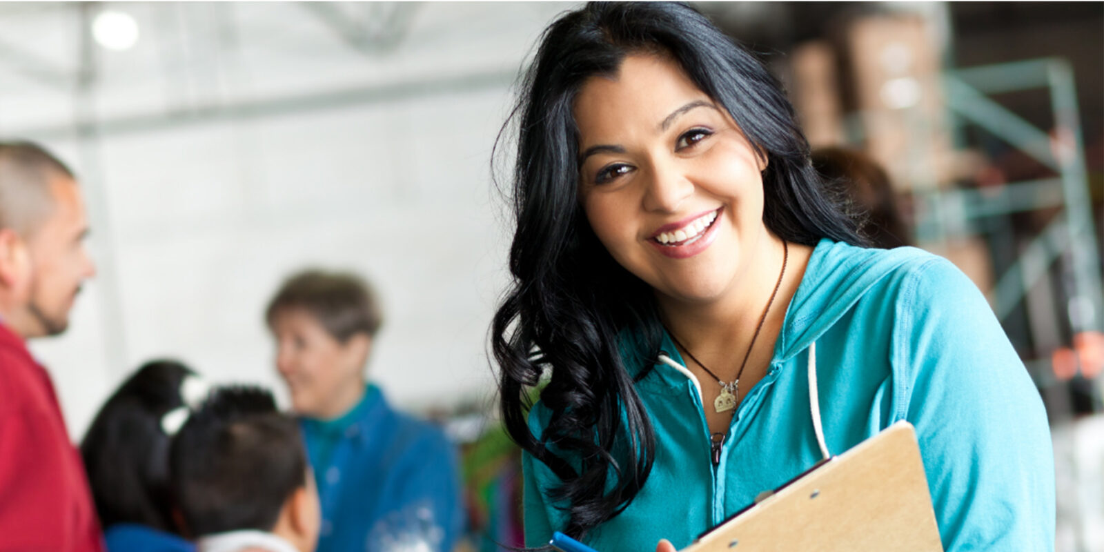 Social worker smiling while holding a clipboard at a community service or donation center